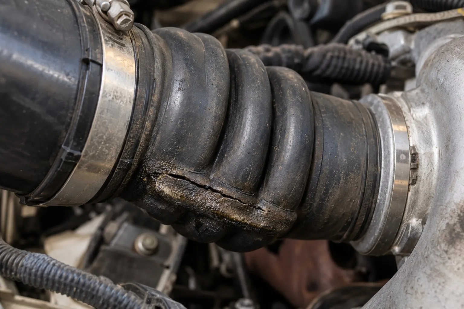How to Replace a Turbocharger Inlet Pipe and Bellows: Step-by-Step 1 Close-up of a cracked lower convolution and oily clamp edge on a diesel turbo inlet bellows
